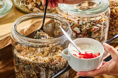 a person holding a cup of granola in jars at Postillion Hotel Amsterdam in Amsterdam
