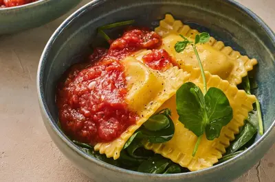 a bowl of pasta with tomato sauce and basil at Postillion Hotel Amsterdam in Amsterdam