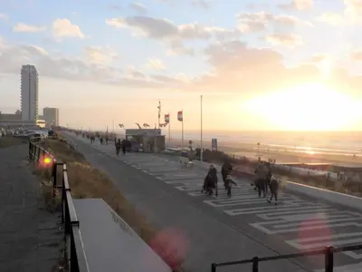 a group of people walking down a road near the beach at Hotel / Pension Villa Tanahlot in Zandvoort