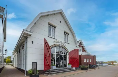 a white building with red doors on a street at Fletcher Hotel - Restaurant Nautisch Kwartier in Huizen