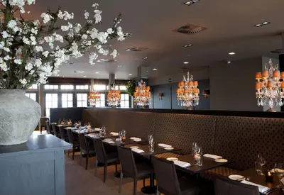 a dining room with tables and chairs and a vase of flowers at Fletcher Hotel - Restaurant Nautisch Kwartier in Huizen
