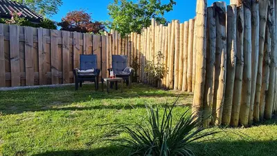 two chairs and a table in a yard next to a fence at At the Dunes in Egmond aan den Hoef