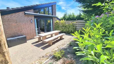 a wooden bench sitting outside of a brick building at At the Dunes in Egmond aan den Hoef