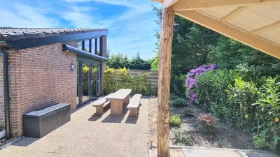 a patio with two benches and a brick building at At the Dunes in Egmond aan den Hoef