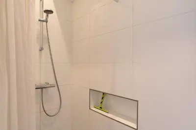 a white bathroom with a shower with a mirror at City centre studio canal belt in Amsterdam