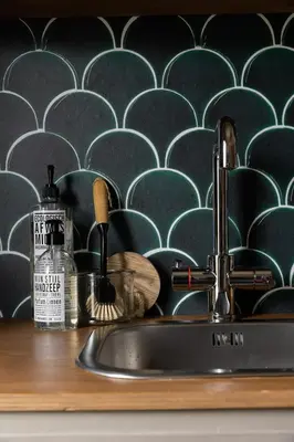 a sink in a kitchen with a wall with blue and white tiles at De oude slaght- luxe suite met buitensauna in Zaandam