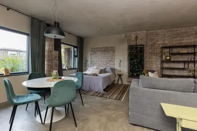 a living room with a bed and a table and a couch at De oude slaght- luxe suite met buitensauna in Zaandam