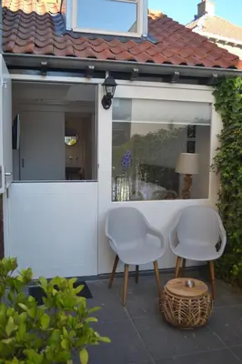 two white chairs and a table on a patio at Behind the Beach in Zandvoort