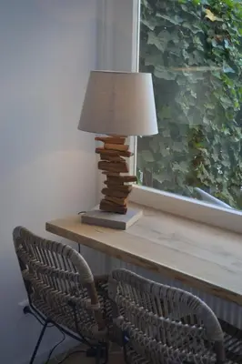 a table with a lamp and a chair and a window at Behind the Beach in Zandvoort