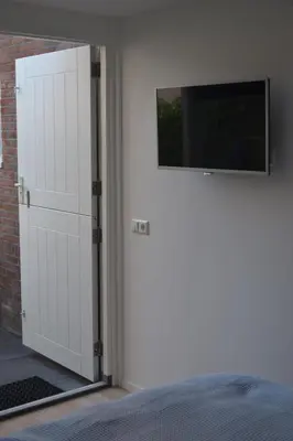 a door to a bedroom with a television on the wall at Behind the Beach in Zandvoort