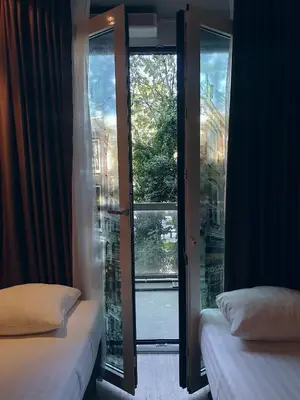a room with two beds and a window with a view at Hotel Mosaic City Centre in Amsterdam
