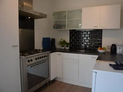 a kitchen with white cabinets and a stove at Bungalow in Noordwijk near Lake & Beach in Noordwijkerhout