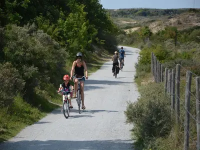 a group of people riding bikes down a road at Bungalow in Noordwijk near Lake & Beach in Noordwijkerhout