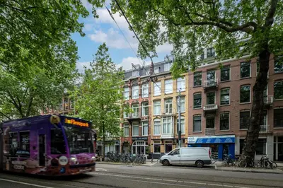 a purple bus is driving down a city street at Hotel Atlantis Amsterdam in Amsterdam