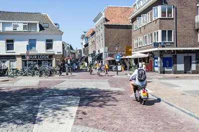 a person riding a scooter on a city street at De Hoendervorst in Utrecht