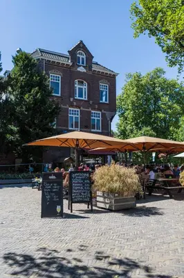 people sitting at tables under umbrellas in front of a building at De Hoendervorst in Utrecht