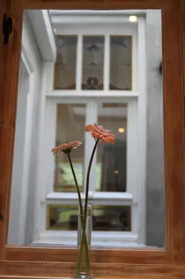 a vase with flowers in front of a window at Bed & Breakfast The 9 Streets in Amsterdam