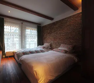 a bedroom with two beds and a brick wall at Bed & Breakfast The 9 Streets in Amsterdam