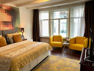 a hotel room with a bed and two yellow chairs at Amsterdam 4 Holiday GuestRooms in Amsterdam