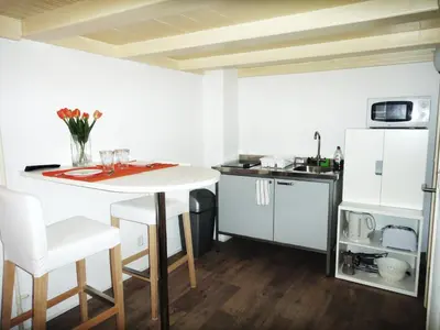 a kitchen with a white table and a white refrigerator at Orange Suite Studio in Amsterdam