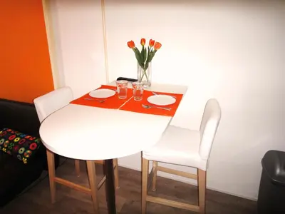 a white table with two chairs and a vase of flowers at Orange Suite Studio in Amsterdam