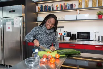a woman standing in a kitchen preparing food at MEININGER Hotel Amsterdam City West in Amsterdam