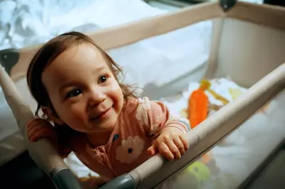 a little girl is sitting in a crib at MEININGER Hotel Amsterdam City West in Amsterdam