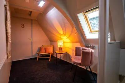 an attic room with two chairs and a window at Bambu Sleep Boutique in Haarlem