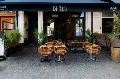 a group of tables and chairs in front of a restaurant at Bambu Sleep Boutique in Haarlem