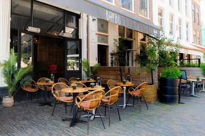 a group of tables and chairs in front of a restaurant at Bambu Sleep Boutique in Haarlem