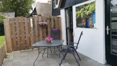 a table and chairs on a patio with a fence at Appartement Zandwerven 23 in Spanbroek