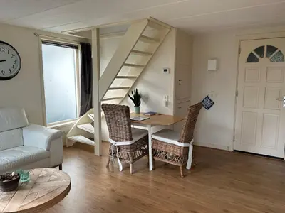 a living room with a table and a spiral staircase at Appartement Zandwerven 23 in Spanbroek