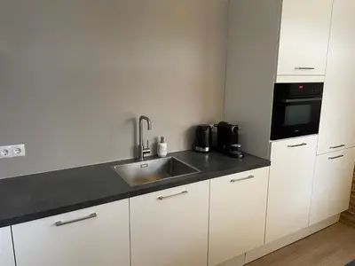 a kitchen with white cabinets and a sink and a microwave at Bed en Beach in Katwijk aan Zee