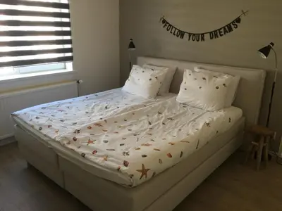 a white bed with a sign that reads thank you them at Bed en Beach in Katwijk aan Zee