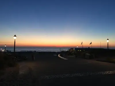a beach at sunset with people walking on the beach at Bed en Beach in Katwijk aan Zee