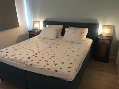 a bed in a bedroom with two night stands and two lamps at Bed en Beach in Katwijk aan Zee