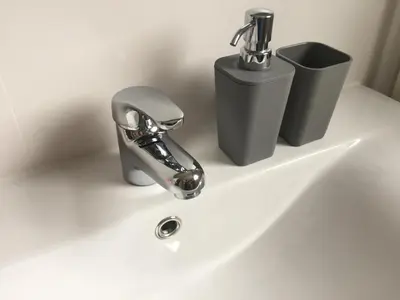 a bathroom sink with a faucet and a trash can at Bed en Beach in Katwijk aan Zee