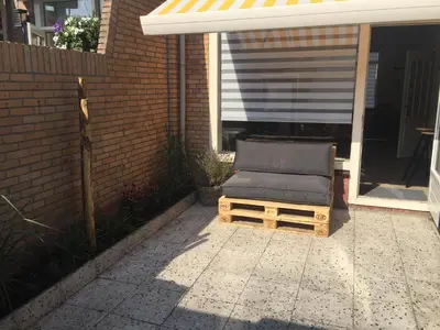 a chair sitting on a porch next to a building at Bed en Beach in Katwijk aan Zee