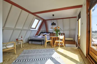 a room with a bed and a table and chairs at Rooftop studio near Amsterdam Castle (Muiden) in Muiden