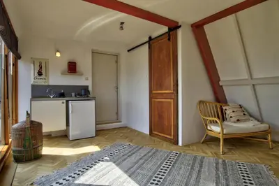 a bedroom with a bed and a chair and a kitchen at Rooftop studio near Amsterdam Castle (Muiden) in Muiden