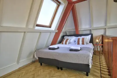 a bedroom with a bed in a attic with a window at Rooftop studio near Amsterdam Castle (Muiden) in Muiden