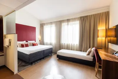 a hotel room with two beds and a desk at City Hotel Gouda, WorldHotels Crafted Collection in Gouda