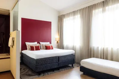 a hotel room with two beds and a red wall at City Hotel Gouda, WorldHotels Crafted Collection in Gouda