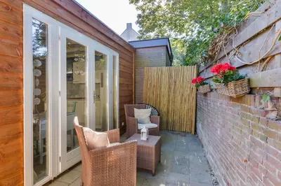 a patio with wicker chairs and a table with flowers at Moyo Kijani in Zandvoort
