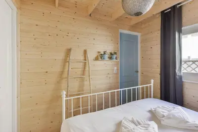 a bedroom with a wooden wall with a bed and a ladder at Moyo Kijani in Zandvoort