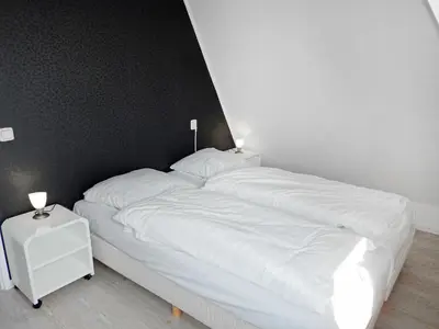 a bed with white sheets and two lamps on it at Holiday Home Plevier Comfort-3 by Interhome in Noordwijkerhout