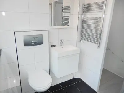 a white bathroom with a toilet and a sink at Holiday Home Plevier Comfort-3 by Interhome in Noordwijkerhout