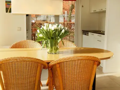 a vase of flowers sitting on a table with chairs at Holiday Home Stern Comfort-3 by Interhome in Noordwijkerhout