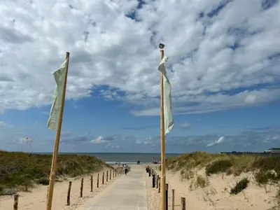 two flags on poles on a sandy beach at Holiday Home Stern Comfort-3 by Interhome in Noordwijkerhout