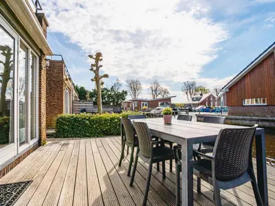 a wooden deck with a table and chairs at Holiday Home Assum by Interhome in Uitgeest